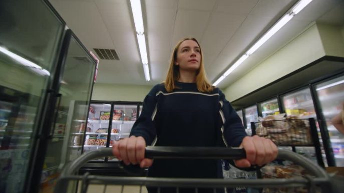 A woman pushing a cart down a grocery aisle
