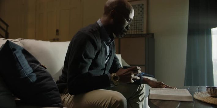 A man on a couch with his phone and Bible