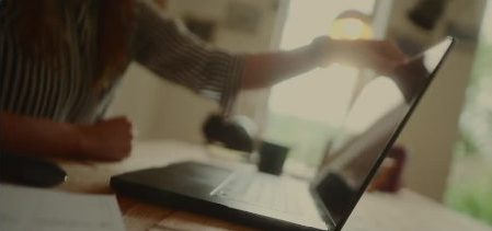 A hand closing a laptop