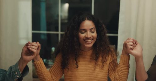 A woman smiling with eyes closed, holding hands in prayer